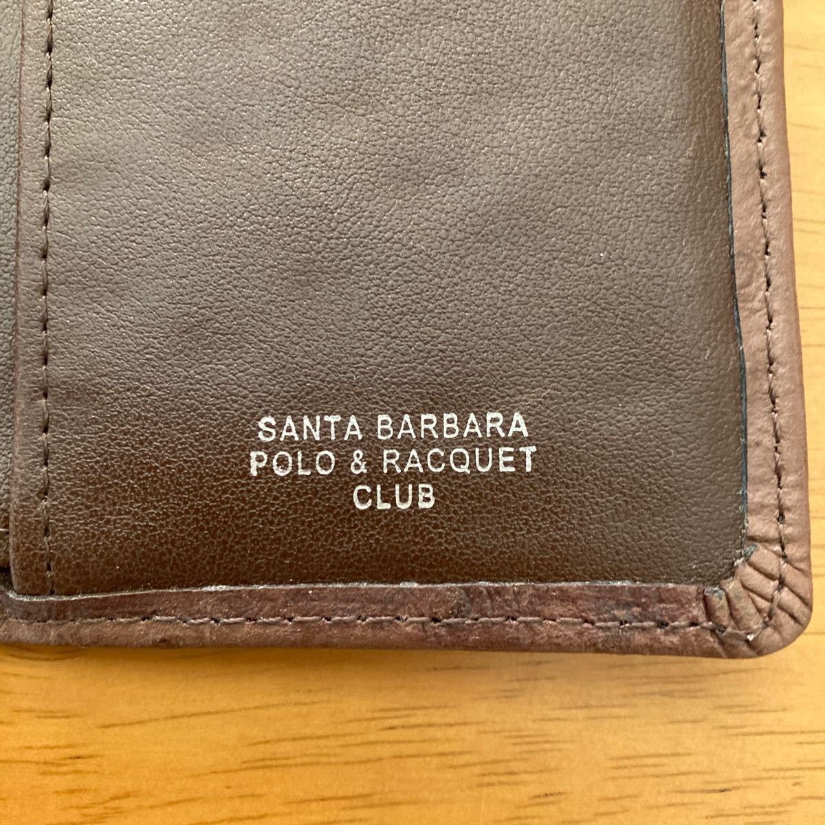 革財布。SANTA BARBARA POLO & RACQUET CLUBのプリントあり。自宅保管品の中古品です。こげ茶色です。