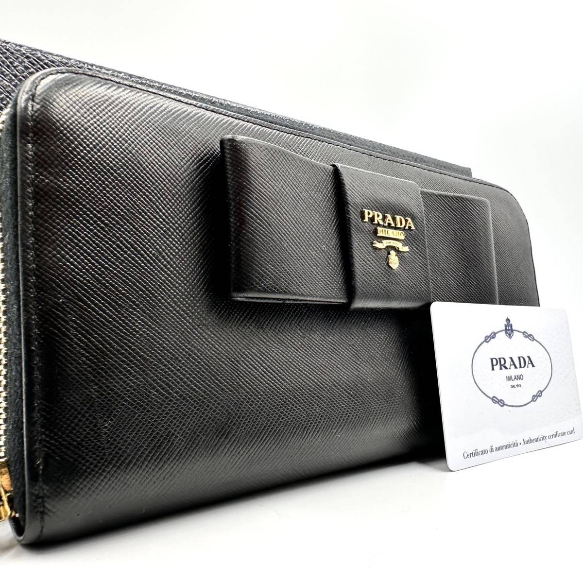 654【美品】PRADA プラダ 長財布 ウォレット ラウンドジップ ファスナー ロゴ 金具 メタル リボン サフィアーノレザー 本革 ブラック 黒色_画像1