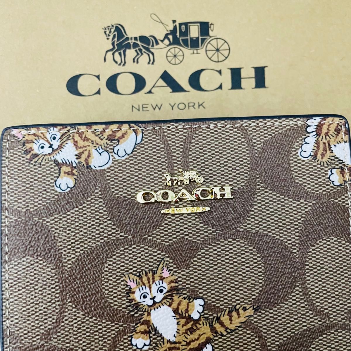 Coachコーチレディース二つ折りミニ財布　新品　ブラウン色カワイイ　キャットプリント柄 ウォレット Cチャーム