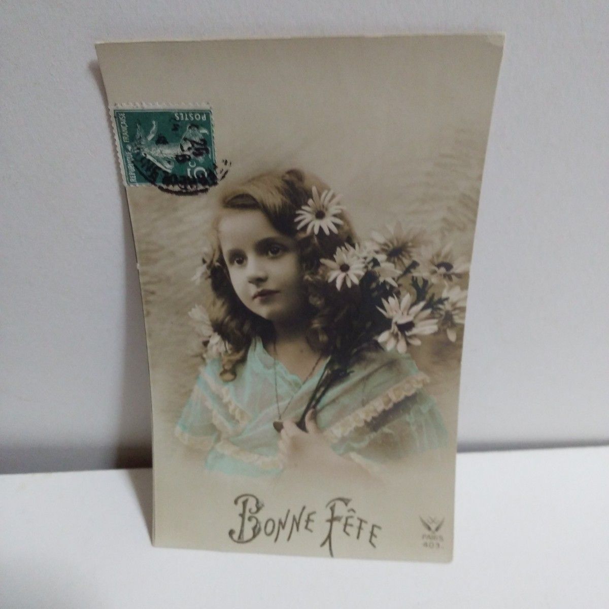 アンティークポストカード　ガーベラの花束を持つブルードレスの少女
