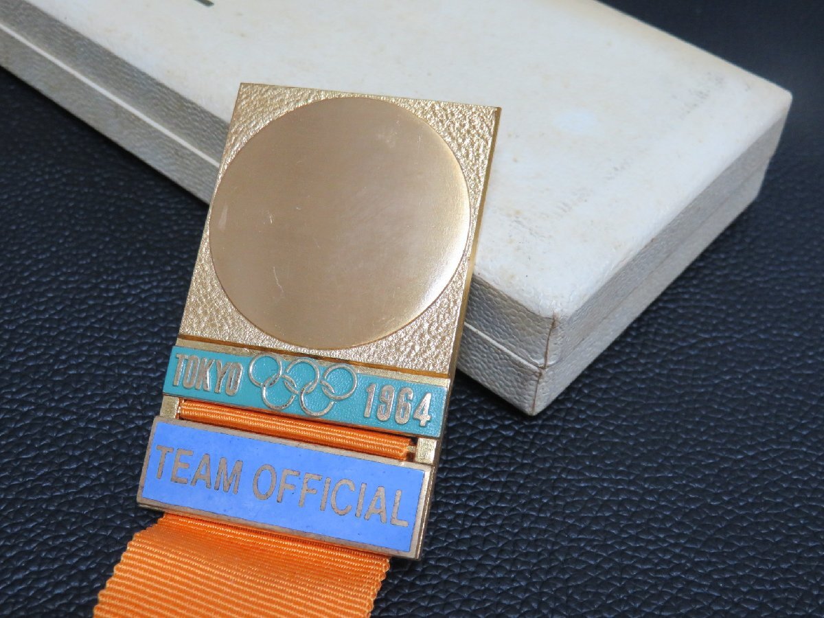 136MAY05【横浜古物】1964 オリンピック 東京大会 TEAM OFFICIAL バッジ  オレンジ色リボンの画像1