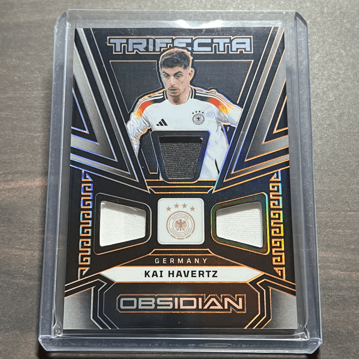 Kai Havertz - Germany Memorabilia /99 Trifecta Material Electric Etch Orange 2023-24 Panini Obsidian Soccer